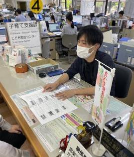 窓口で職員がカウンターに書類を広げて来庁者に説明している様子