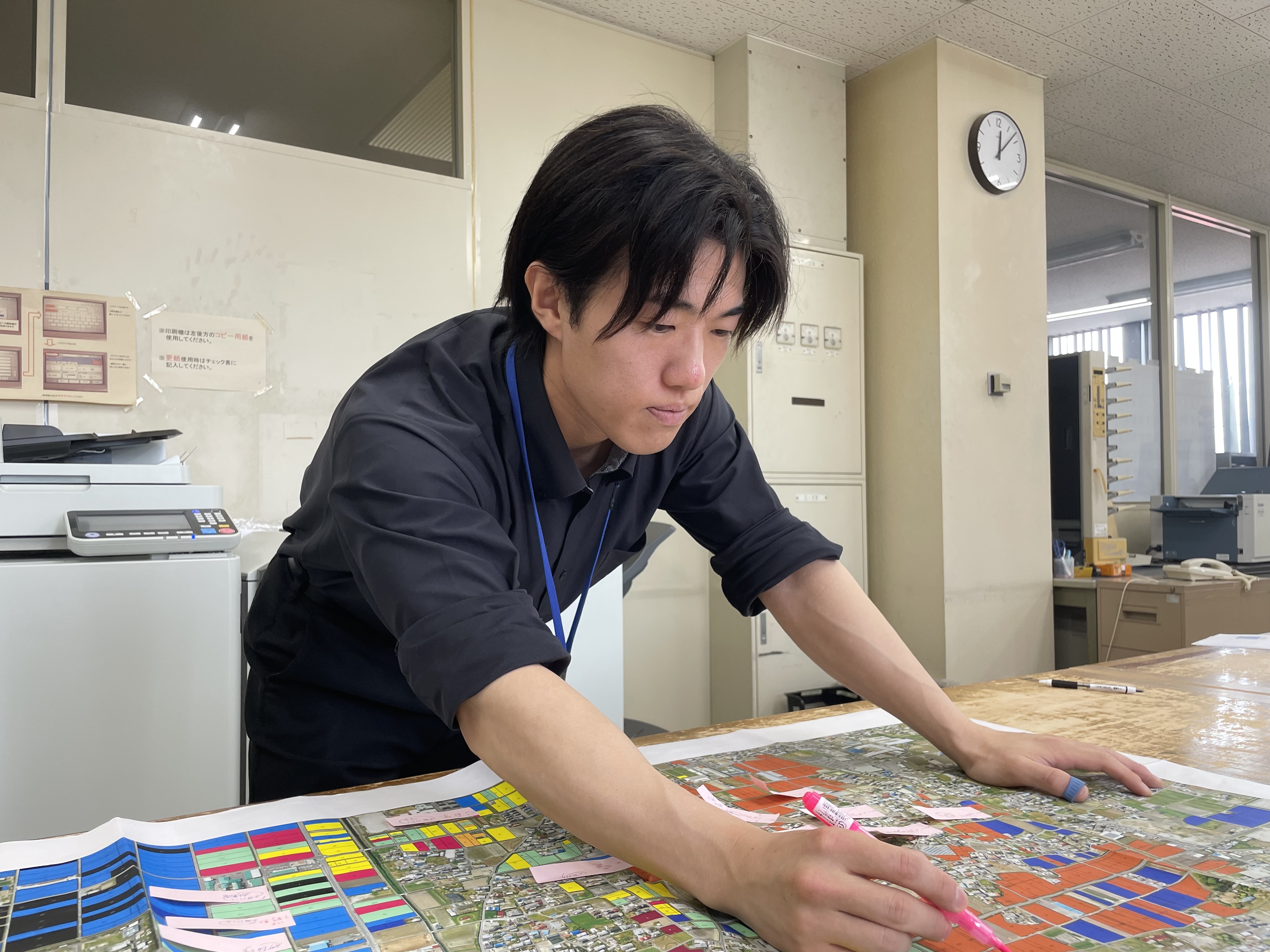 テーブルに広げた地図に身を乗り出してマーカーで書き込みをしている人物